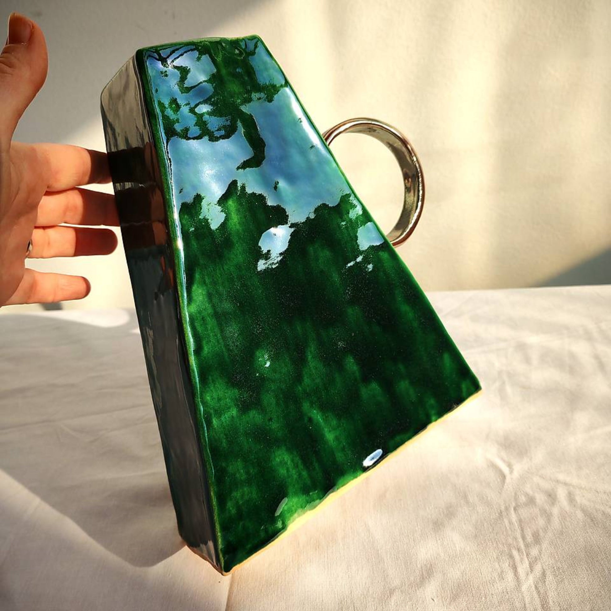 Glossy green ceramic vase with metal looking handle 