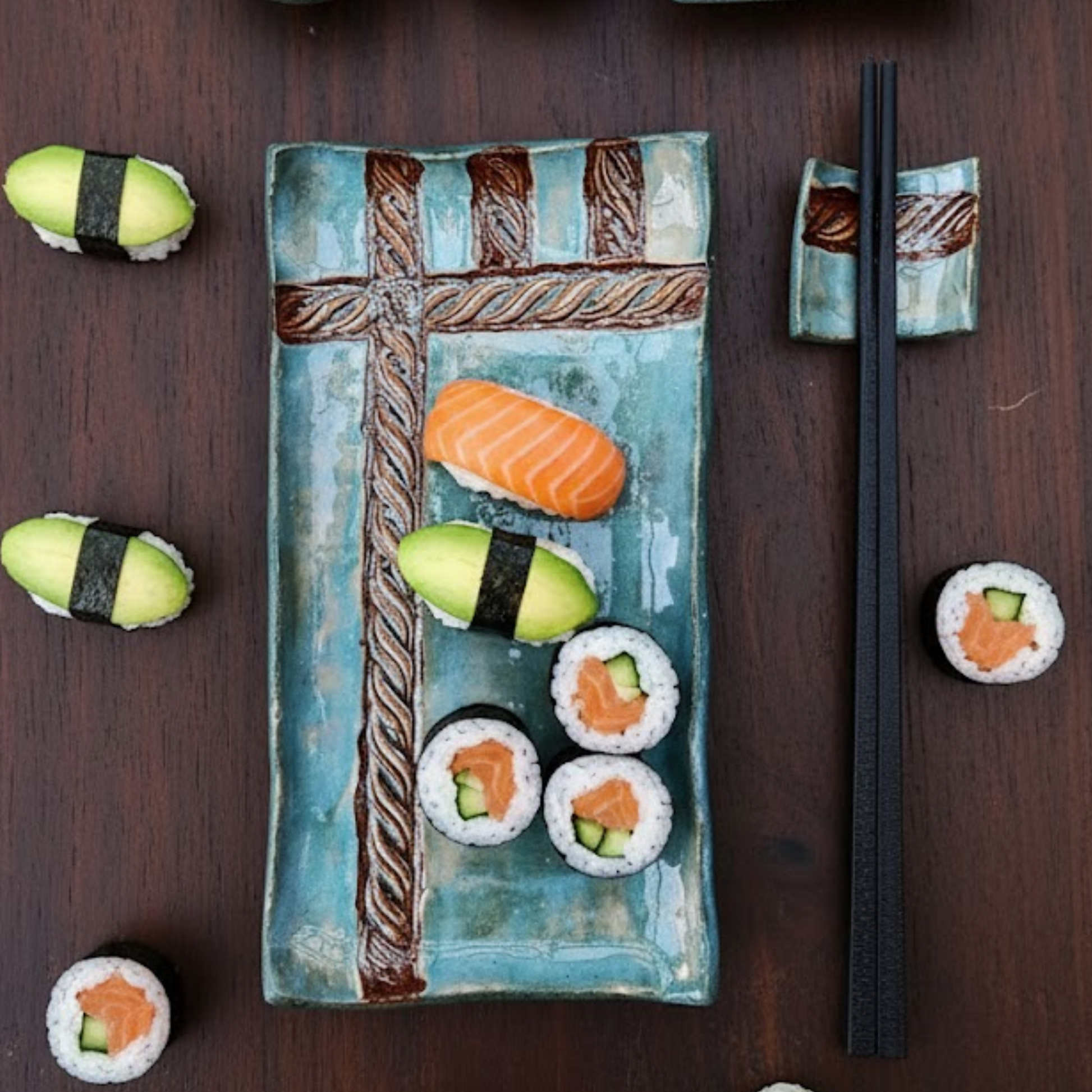 Handmade 2-piece turquoise ceramic sushi set with a rectangular plate, two dipping bowls, and a chopstick rest, featuring an embossed rope pattern and styled with fresh sushi.